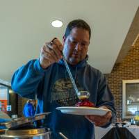 Person adding strawberries to pancakes in Kirkhof Center lobby.